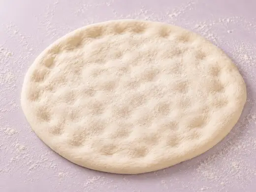 Rolled pizza dough balls on a floured surface