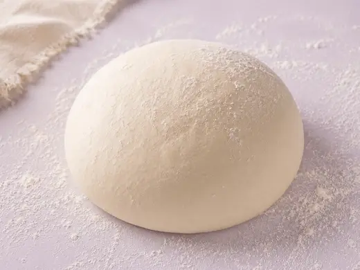 Two pizza dough balls dusted with flour